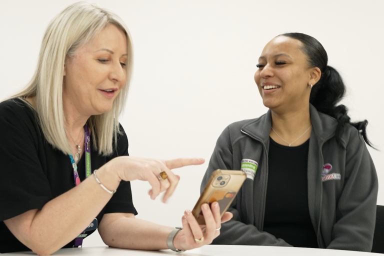 This is a picture of two women sitting at a table looking at a mobile phone